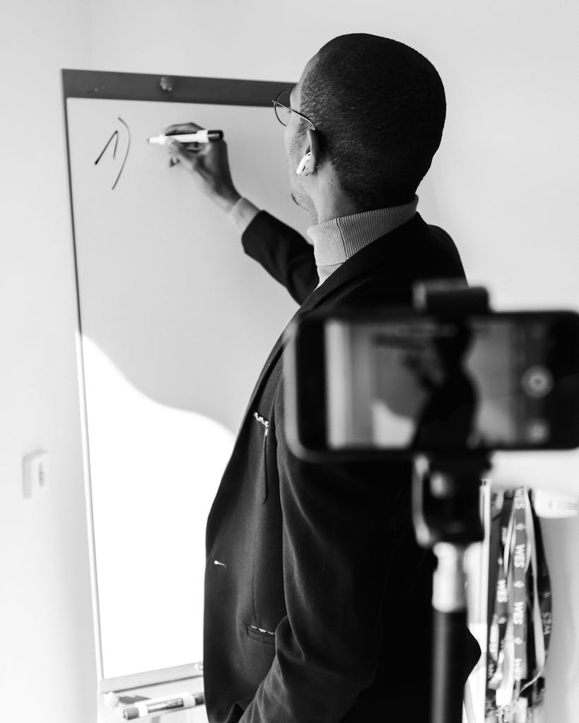 A man in a suit writing on a whiteboard